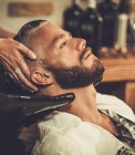 Hairstylist washing client's hair in barber shop